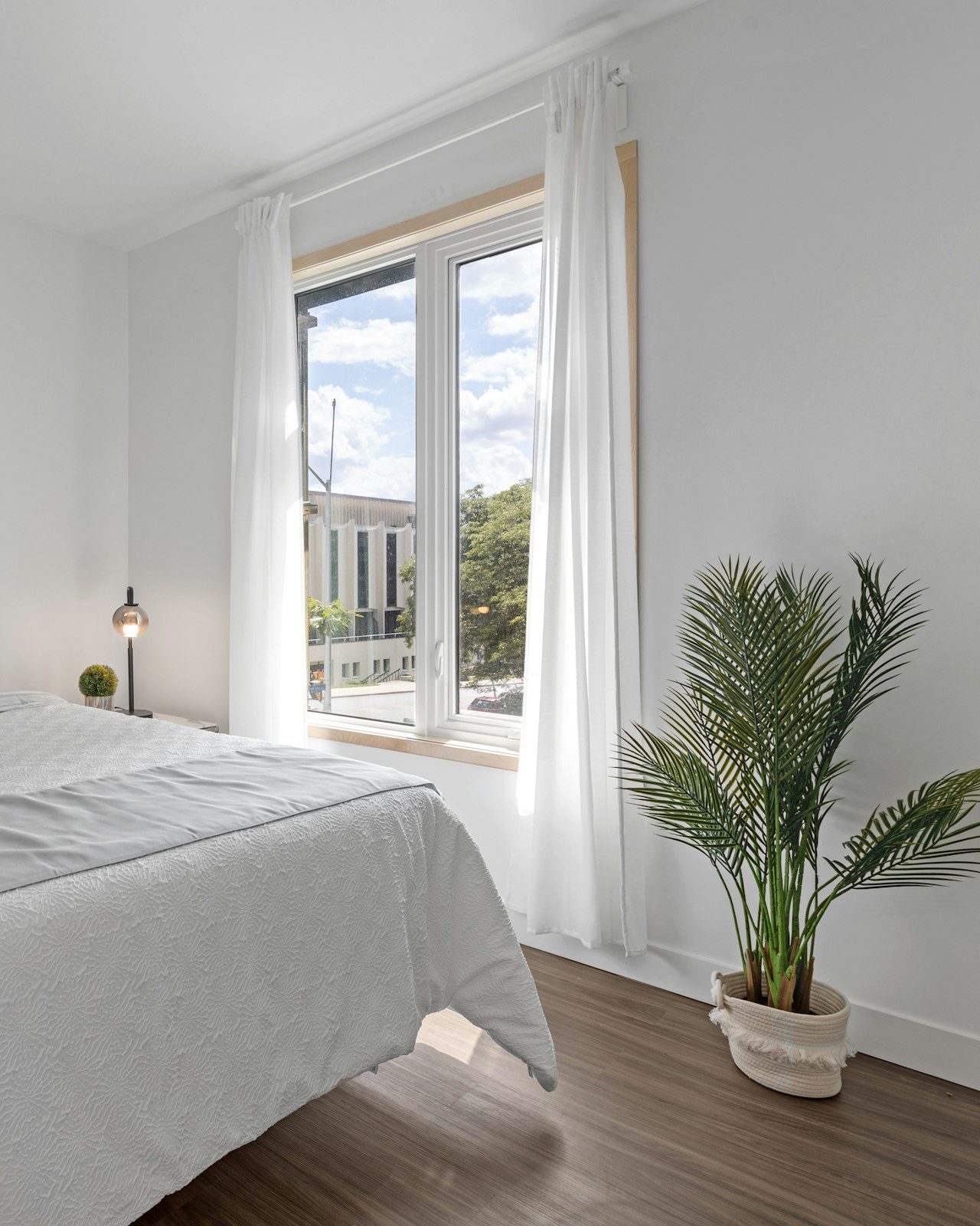 Bright furnished bedroom with daylight from a large window and a made bed