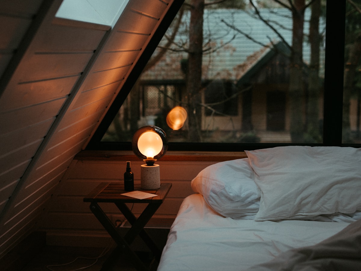 A private furnished room with a bed and warm nightstand lamp